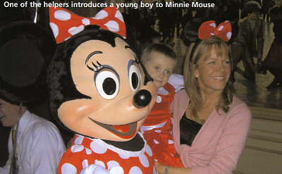 One of the helpers introduces a young boy to Minnie Mouse
