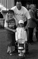 A delighted Lee Pearce shows off his two children and the championship trophy