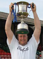 In his DaC t-shirt, Lee holds up the championship cup Bedfont Green won last season